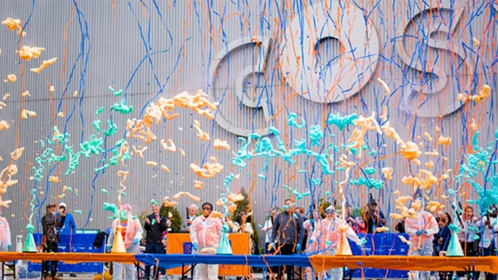 A number of colorful beakers erupt with slime into the air in front of the COSI building