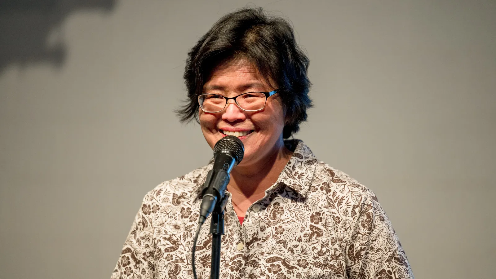 A woman standing behind a microphone talking