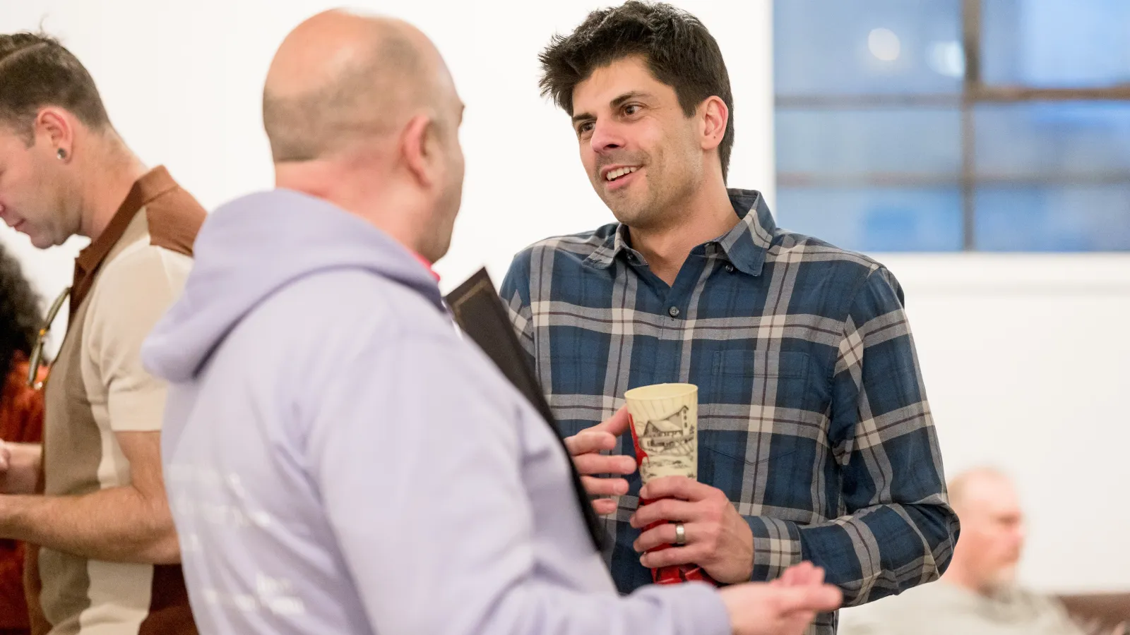 Two men talking, one smiling and the other with their back to the camera