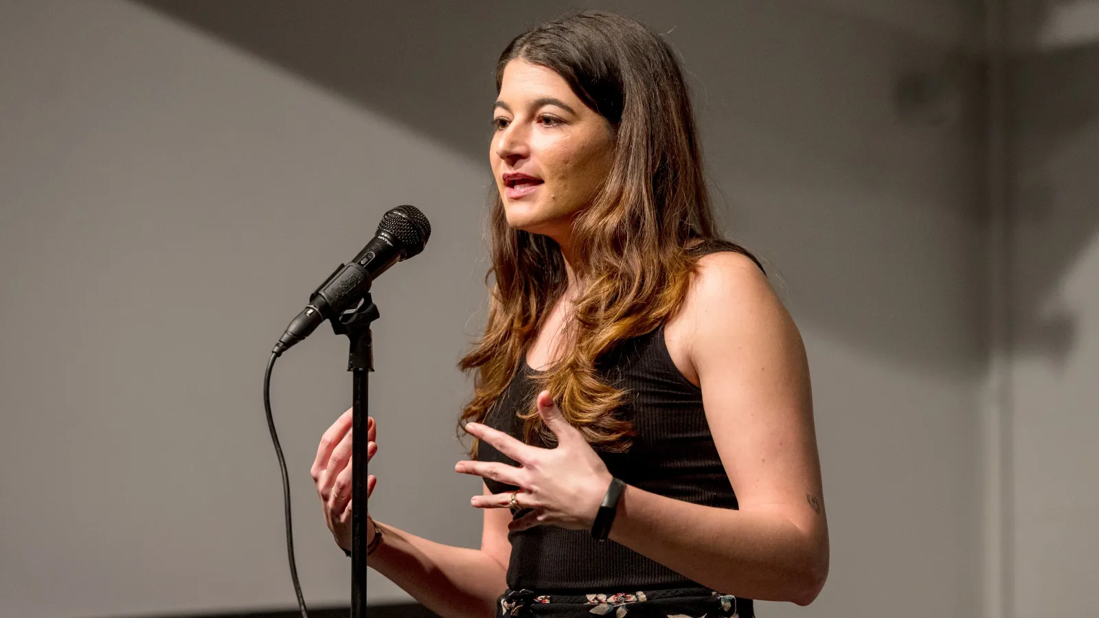 A woman standing at a microphone speaking