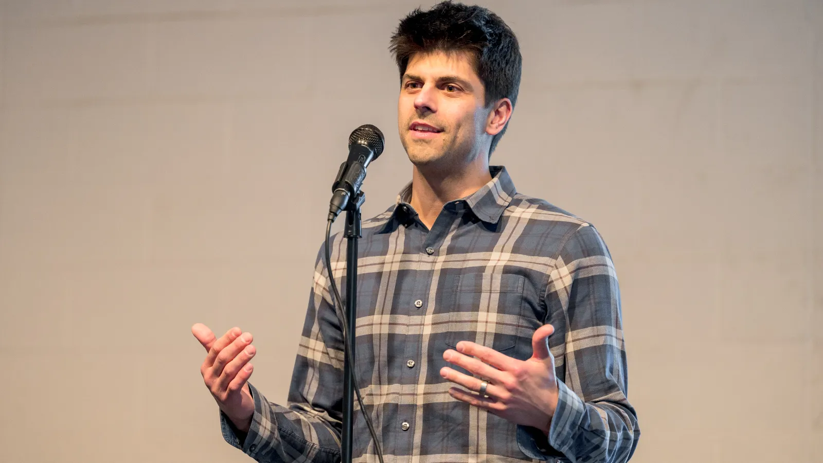Jesse Plascak telling a story on stage behind a microphone