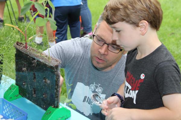 an adult and a child examining plants growing from a transparent planter