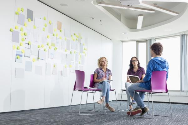 Three people having a chat inside a big white room 