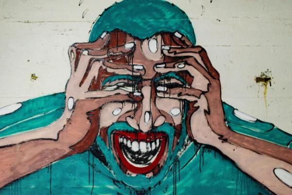 Mural on a wall of a man showing extreme signs of stress