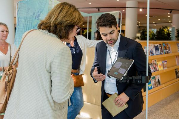 Man explains as woman engages in interactive screen