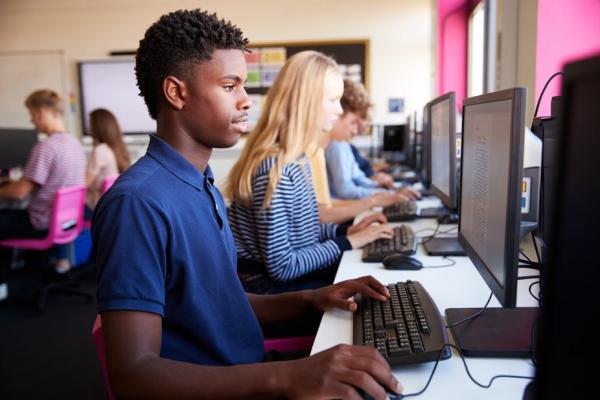 seven students are featured on screen using computers for word processing in a classroom setting