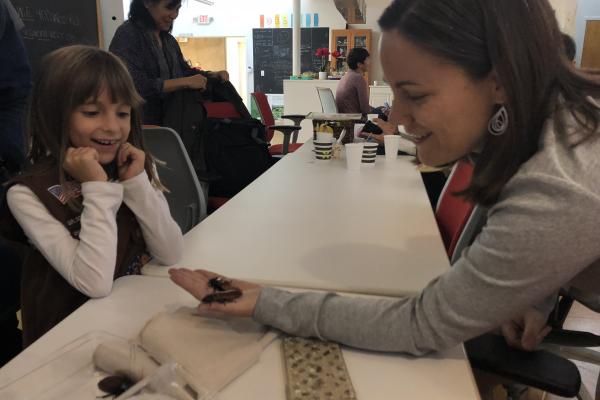 woman holding two beetles out for a young girl who is excited