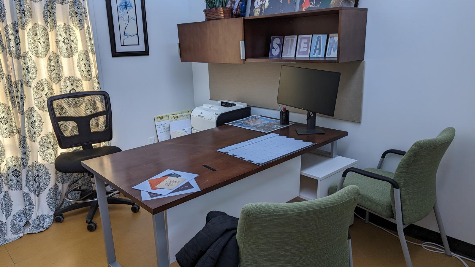 A small office space that is attached to our main space. The space features a desk with three chairs.