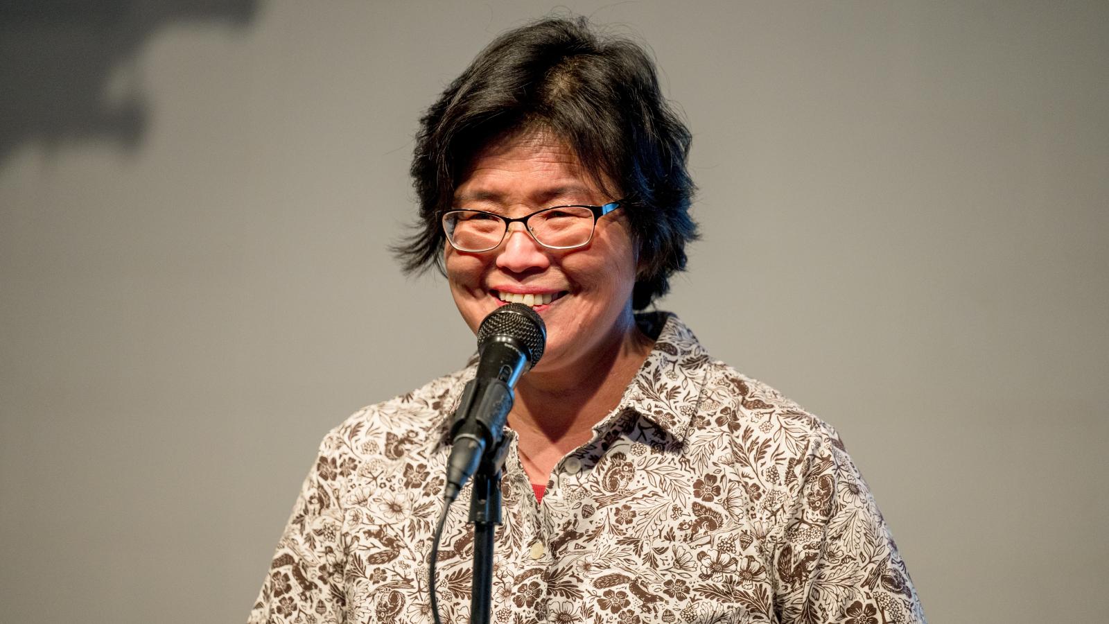 A woman standing behind a microphone talking