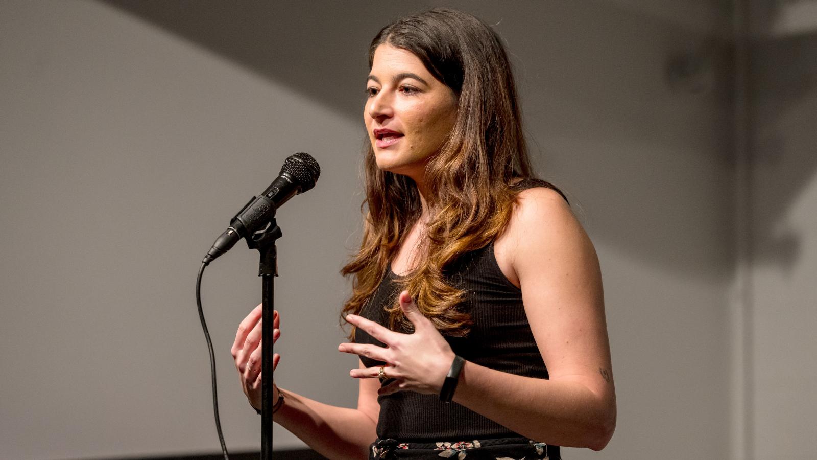A woman standing at a microphone speaking
