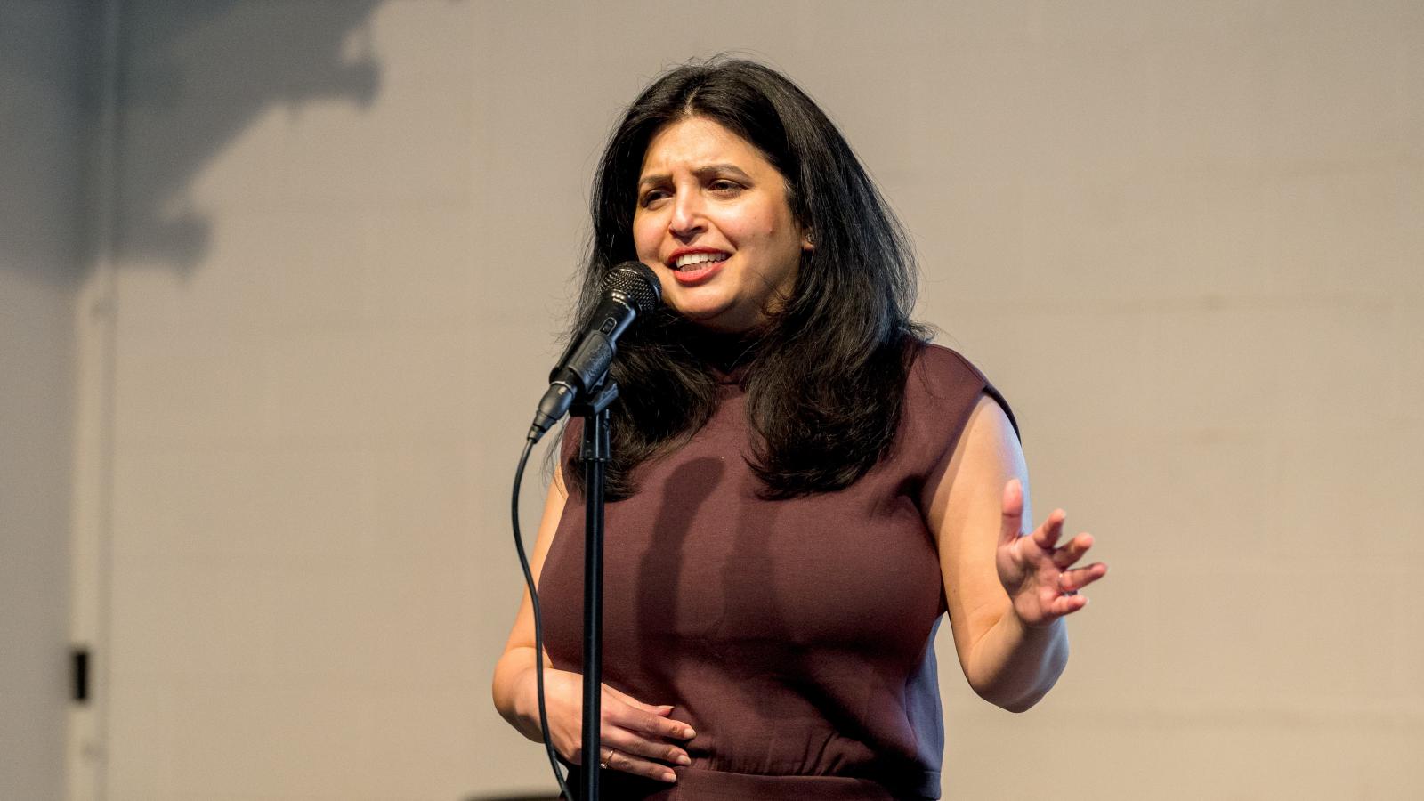 A woman standing behind a microphone speaking