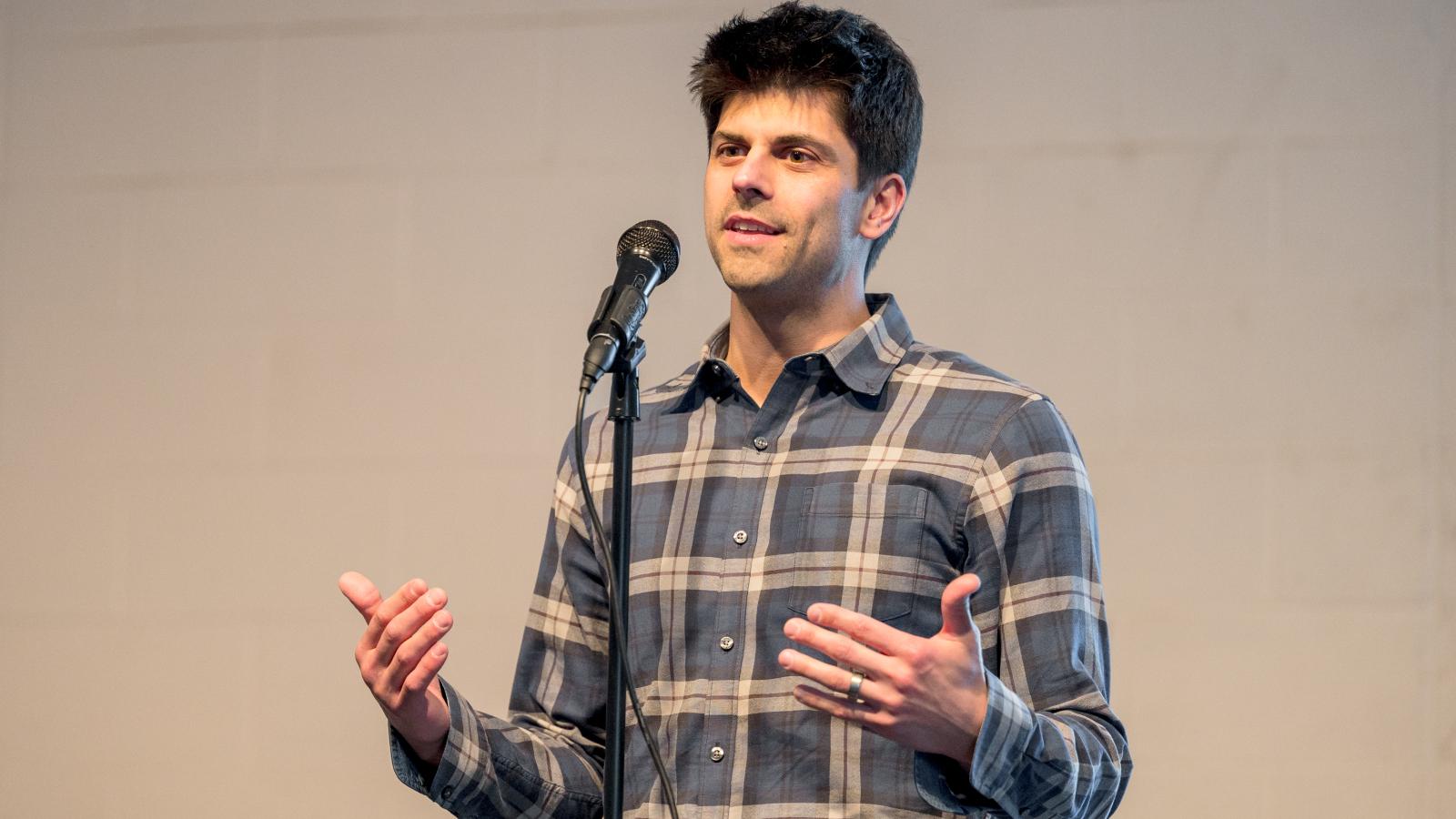 Jesse Plascak telling a story on stage behind a microphone